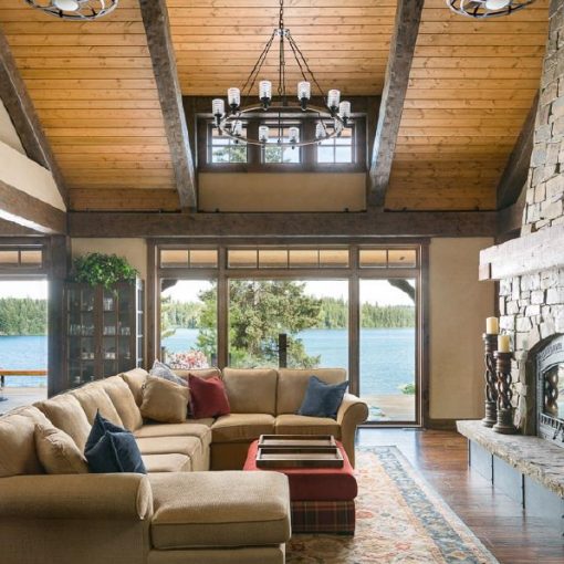 Interior of Timber Frame home in Bridge Lake, BC showing fireplace, living room and view of lake out the windows